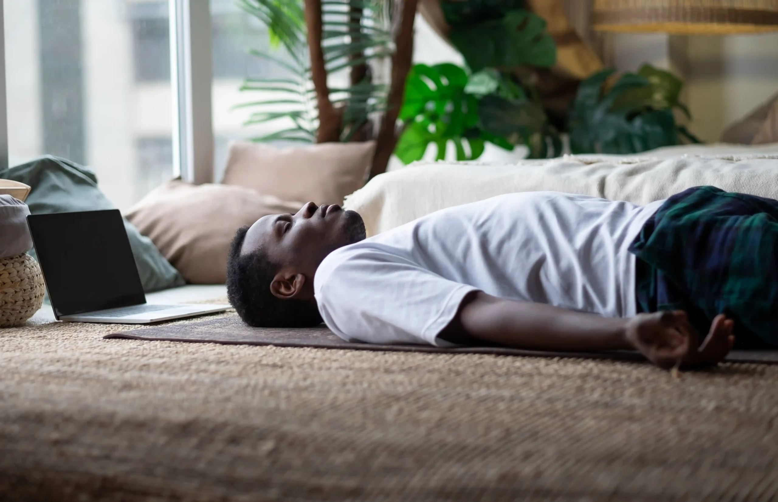 Homme allongé au sol, sur un tapis, en Shavasana.