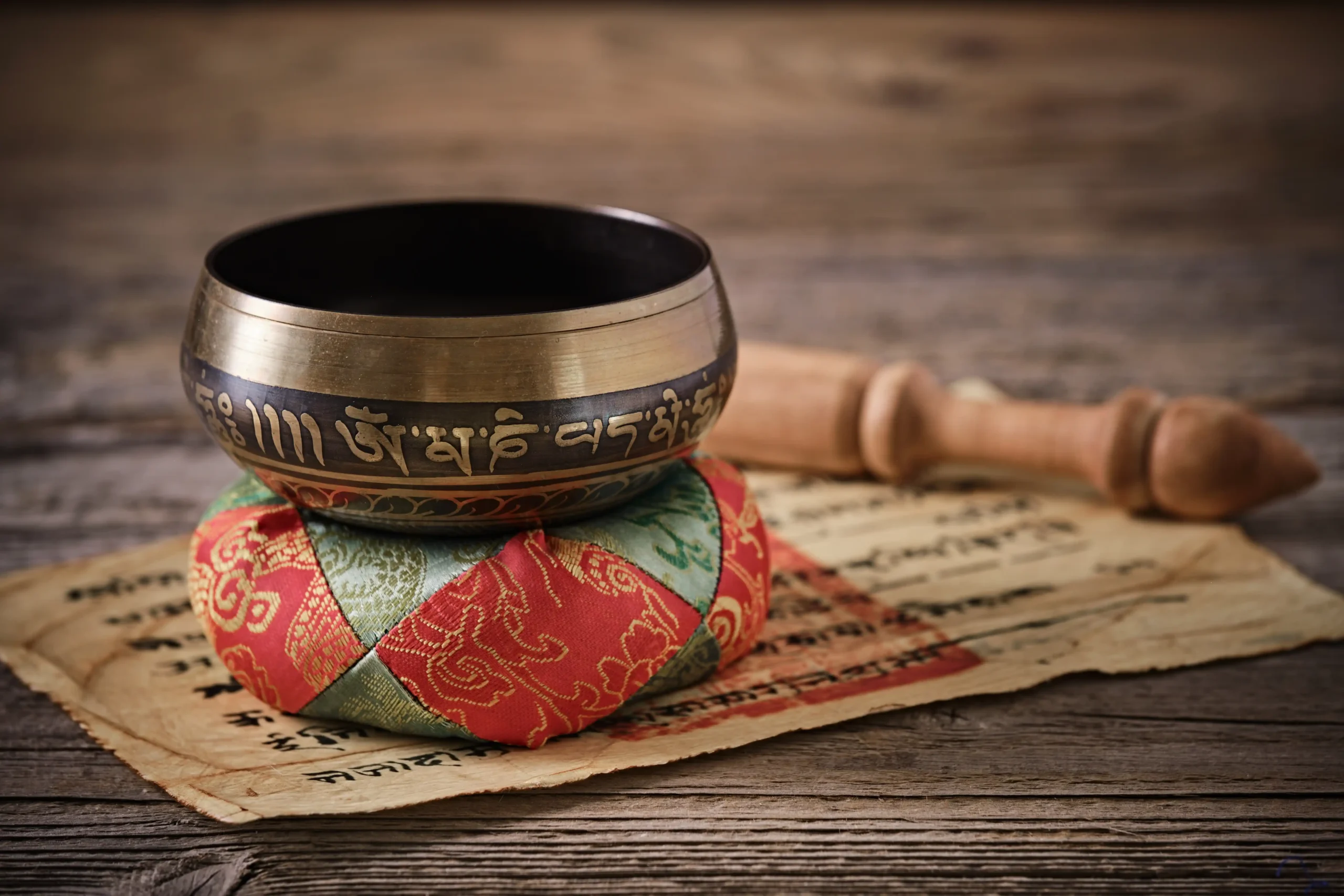 Bol chantant avec mantra gravé « Om Mani Padme Hum » sur une table en bois.